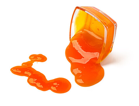 Orange jam spilling from a glass bowl