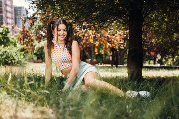 Young girl in a park enjoying a sunny day wearing a checkered crop top and denim skirt for a casual...