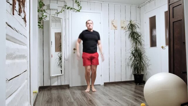 Caucasian man doing an exercise Jumping Jacks on at home. Fast workout. Morning warmup. Strengthening the muscles of legs, endurance and balance. Strong sporty body. HQ 4k footage.