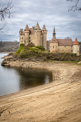 Naklejka premium A majestic wide-angle shot of the Chateau de Val, a 15th-century fortress situated on the banks of the Bort-les-Orgues reservoir in the Cantal department of Auvergne, France.