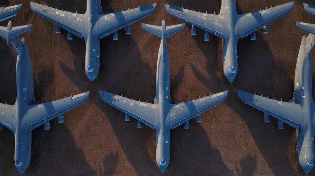 Tucson, United States - 07 April 2026: Aerial view of military transport aircraft parked in neat rows on the desert floor, creating a geometric pattern.