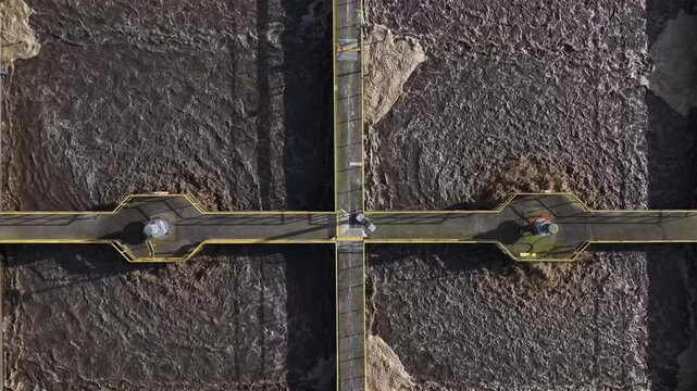 Aerial view of a bridge over a river showcasing the contrast between the turbulent water and the bridge's structure, Lisbon, Portugal.