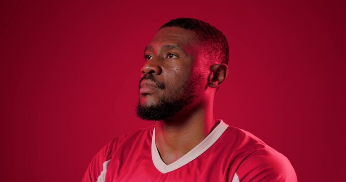 30s African man in red jersey in studio uncrossing as camera closing, meeting camera for portrait