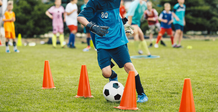 Youth Soccer Dribbling Drill; Kid Running with Ball Between Cones During Training