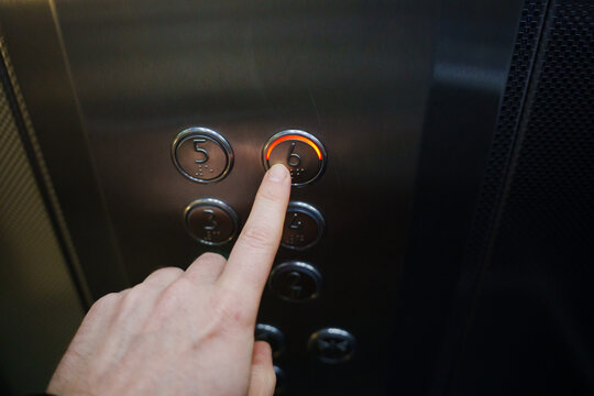 Finger pressing button for sixth floor in elevator at office building