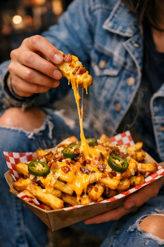 Loaded cheesy fries street food editorial photography of college student taking first bite