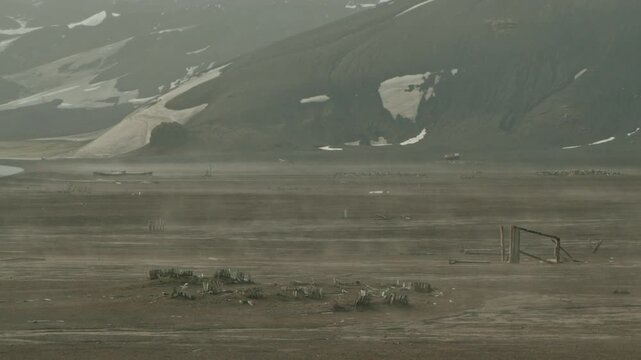 Desolate ash plain at Whalers Bay Deception Island with scattered whaling station ruins wooden debris and collapsed metal frame
