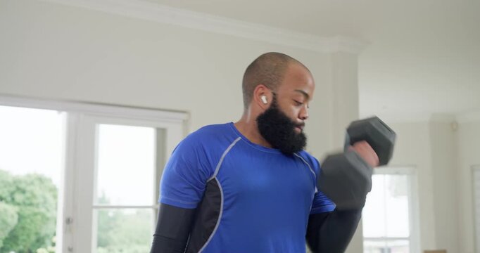 Man breathing, lifting hexweight with earbuds in blue shirt curling for biceps by glass door