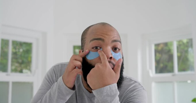 Man holding patch peeling placing smoothing adjusting blue hydrogel patches for skincare at home