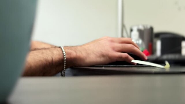 Side view close-up of a hand using a computer mouse at a modern office desk, showing focused indoor computer work, keyboard setup, and professional workspace details.