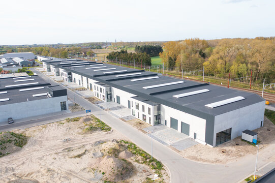 Aerial view of modern industrial buildings standing stark against the muted landscape under a pale sky, Oostkamp, Flanders, Belgium.