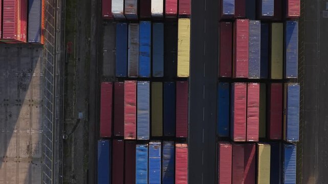 Alicante, Spain - 11 April 2026: Aerial view of rows of stacked, multicolored cargo containers, separated by a narrow road, showcasing industrial organization.