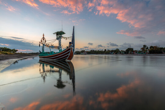 Cinematic Sunset Reflection of a Traditional Ornate Boat on Calm Waters in Jembrana, Bali