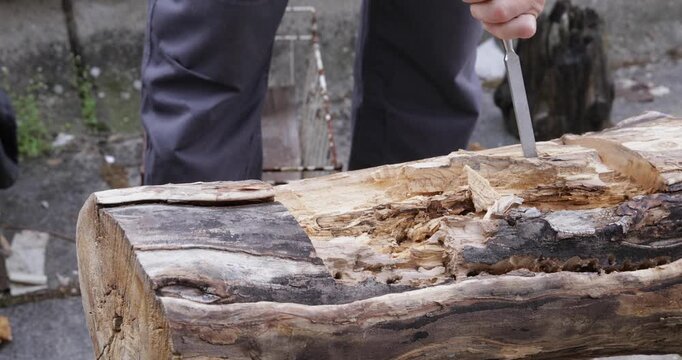 Woodworking carving, crafts-person digging tree trunk using hammer and chisel