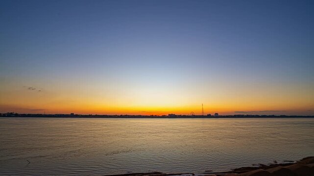 A breathtaking aerial view of Nakhon Phanom at dusk. where twinkling city lights shimmer across the Mekong River. The riverside atmosphere and glowing skyline create a captivating scene perfect
