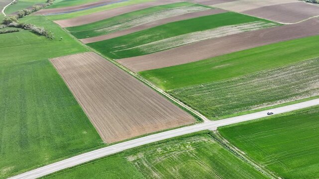 Aerial view of patchwork agricultural fields create a textured tapestry of vibrant greens and earthy browns, Wintzenheim-Kochersberg, Grand Est, France.