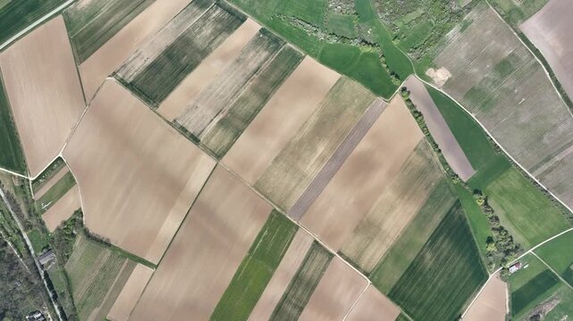 Aerial view of agricultural fields showcasing a patchwork of textures and tones, from verdant greens to earthy browns, Wintzenheim-Kochersberg, Grand Est, France.