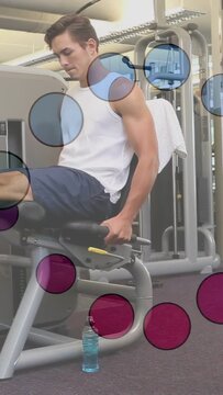 Male mid20s adjusting grip performing leg extensions on gym machine wearing white tank for warmup