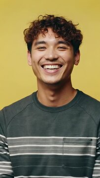 Close-up of a man smiling in front of a yellow background, a young man smiling in the sun with a yellow background