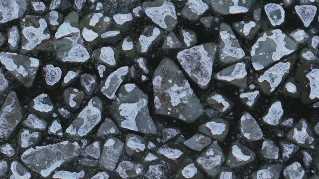 Aerial view of the frozen Baltic sea showing jagged ice floes with frosty edges contrasting against the dark water, Mikoszewo, pomorskie, Poland.
