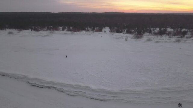 Aerial view of a vast expanse of the frozen Baltic sea, its icy surface textured with subtle ridges and two tiny figures, Mikoszewo, pomorskie, Poland.