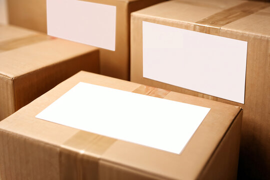 Stacked cardboard boxes with blank white shipping labels mockup. Packaging and delivery concept, ecommerce logistics, parcel shipping and warehouse distribution with copy space.