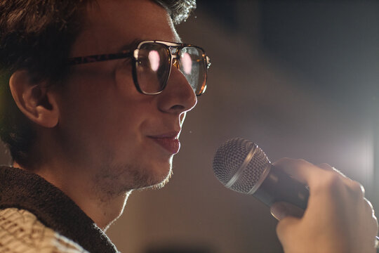 Close up of Caucasian young adult man performing standup comedy on stage, speaking into microphone. Useful for entertainment marketing, live event promotion, comedy branding

