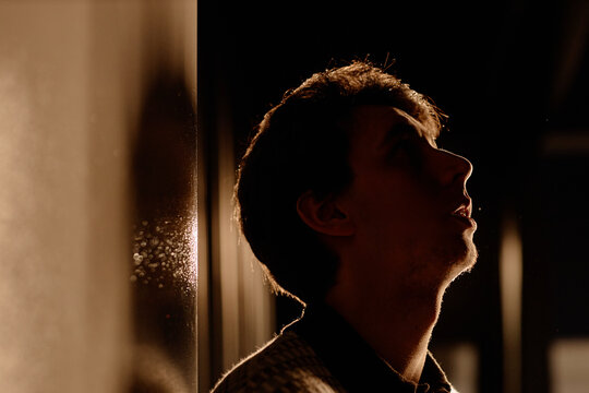 Young adult Caucasian man performing standup on stage, looking upward in side profile and delivering comedic set. Useful for entertainment marketing, live event promotion, medium close up

