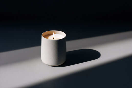 Burning candle in speckled ceramic jar with strong directional light