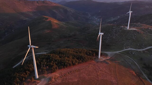 Aerial view of windmills standing tall on rolling hills, kissed by the warm glow of the setting sun, Amarante, Portugal.