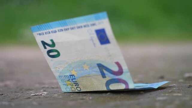 Twenty euro banknote rests on the ground, waiting to be picked up. The scene highlights opportunity, chance, and unnoticed value in a quiet everyday urban setting.