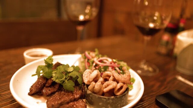 Delicious grilled steak with garnish and crispy fried calamari served on plate with wine glasses.
