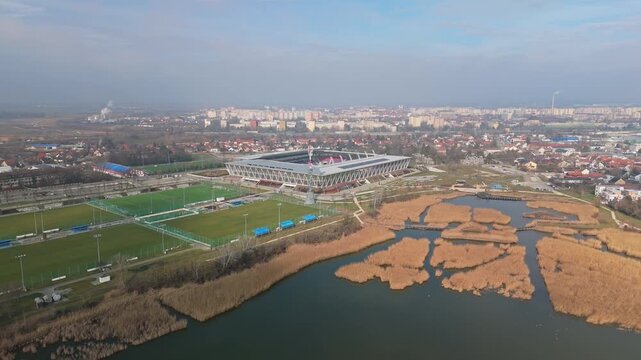 Sz&eacute;kesfeh&eacute;rv&aacute;r&rsquo;s MOL Ar&eacute;na S&oacute;st&oacute;i Stadion, home to Videoton FC, stands near S&oacute;st&oacute; Lake and wetlands, surrounded by urban infrastructure and parkland, seen from an aerial drone perspective.