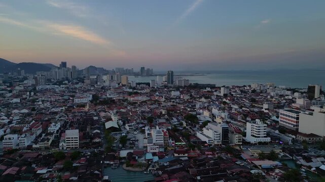 New George Town skyscraper Penang harbor and buildings with stilt houses along the coast under a twilight sky, creating an urban maritime blend. Perfect aerial view rotation pan to right panorama dro