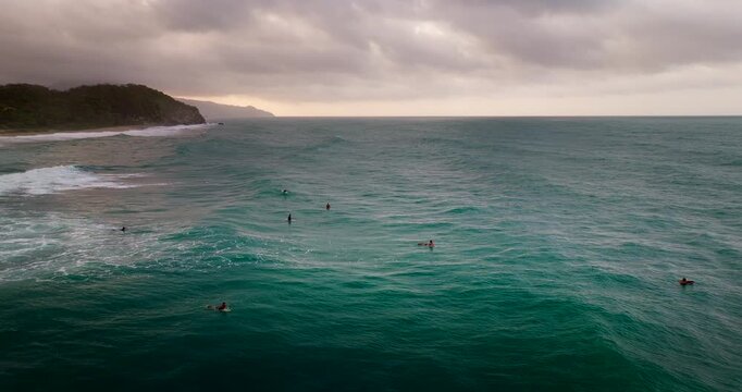 Aerial view of surfers paddling and riding waves in the ocean at Los Naranjos, a popular surf spot near Tayrona Park in Colombia