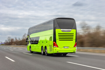 Green double decker bus drives on highway. Modern tourist coach moves along the road. © puhimec