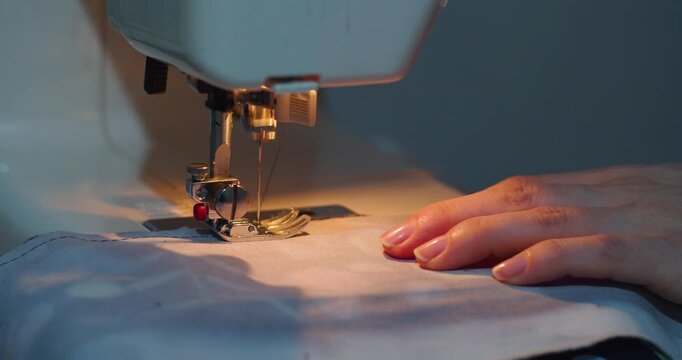 60 fps 4k footage of a hands carefully sew blue fabric using a machine, creating neat stitches. The close-up captures the steady rhythm and attention to detail in the process.