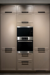Fototapeta premium Built in kitchen with oven in beige cabinets modern interior. Minimalist kitchen furniture design.