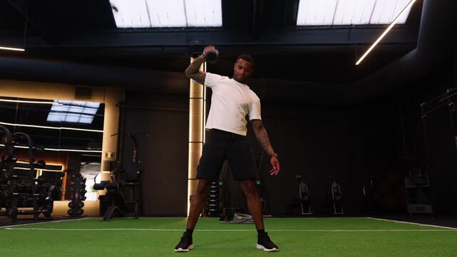 Strong african american man training with kettlebell snatch