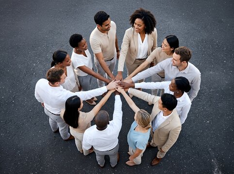 A diverse group of business professionals join hands in a circle, symbolizing teamwork and unity in an HR setting.