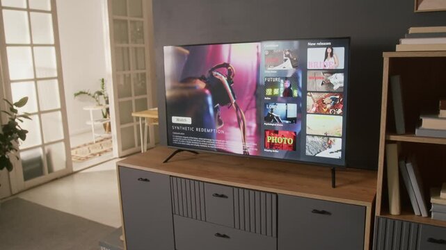 No people zoom-out shot of living room at family home, with TV on drawer in front of couch, demonstrating streaming app menu with selection of sci-fi thriller, crime drama or romantic comedy films