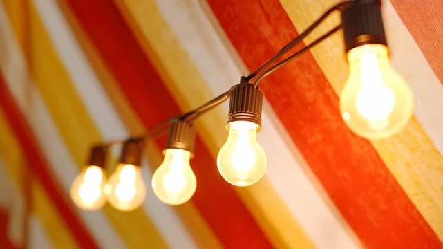 A string of light bulbs elegantly hangs from the ceiling of a tent, creating a warm and inviting atmosphere.