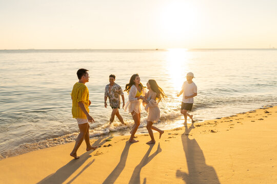 Group of diverse friends having fun playing together on beach at sunset enjoy summer vacation travel laughing and splashing in sea water carefree lifestyle friendship bonding outdoor activity by ocean