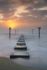 Fototapeta premium view of the remnants of a wooden pier at Carolina Beach in Wilmington t sunrise
