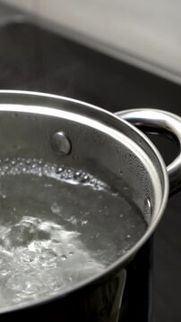 A stainless steel pot with boiling water on an induction stove. Boiling water in a pot.	