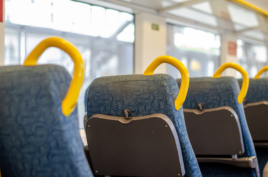 Interior of a regional train in Victoria Australia, with rows of vacant seats and yellow grab handles, showing public transport seating arrangement and passenger space. Modern train carriage design.