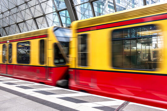 Yellow and red S-Bahn train with motion blur effect. Modern railway station in Berlin.