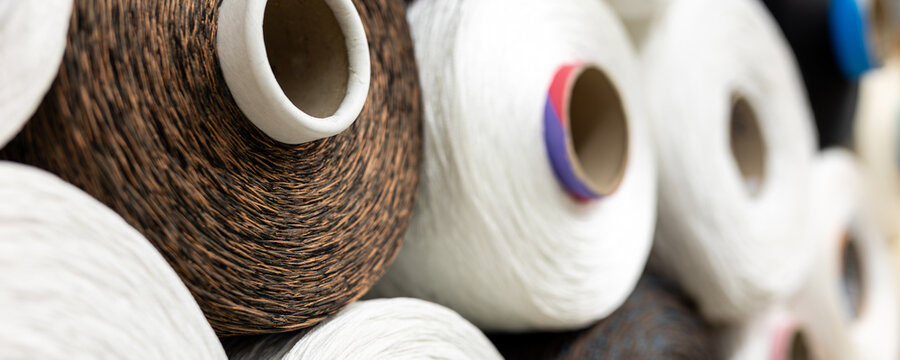 Industrial textile thread spools stacked warehouse fiber production materials visible texture, twist pattern detail. Circular rolls manufacturing process, material quality, order and consistency