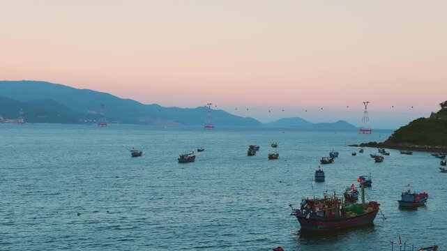 Aerial view of traditional wooden fishing boats in a coastal village in Nha Trang, Vietnam
Dozens of wooden fishing boats with red flags are anchored in a calm harbor at sunset.