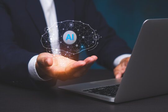 Business person holding AI hologram over laptop computer
